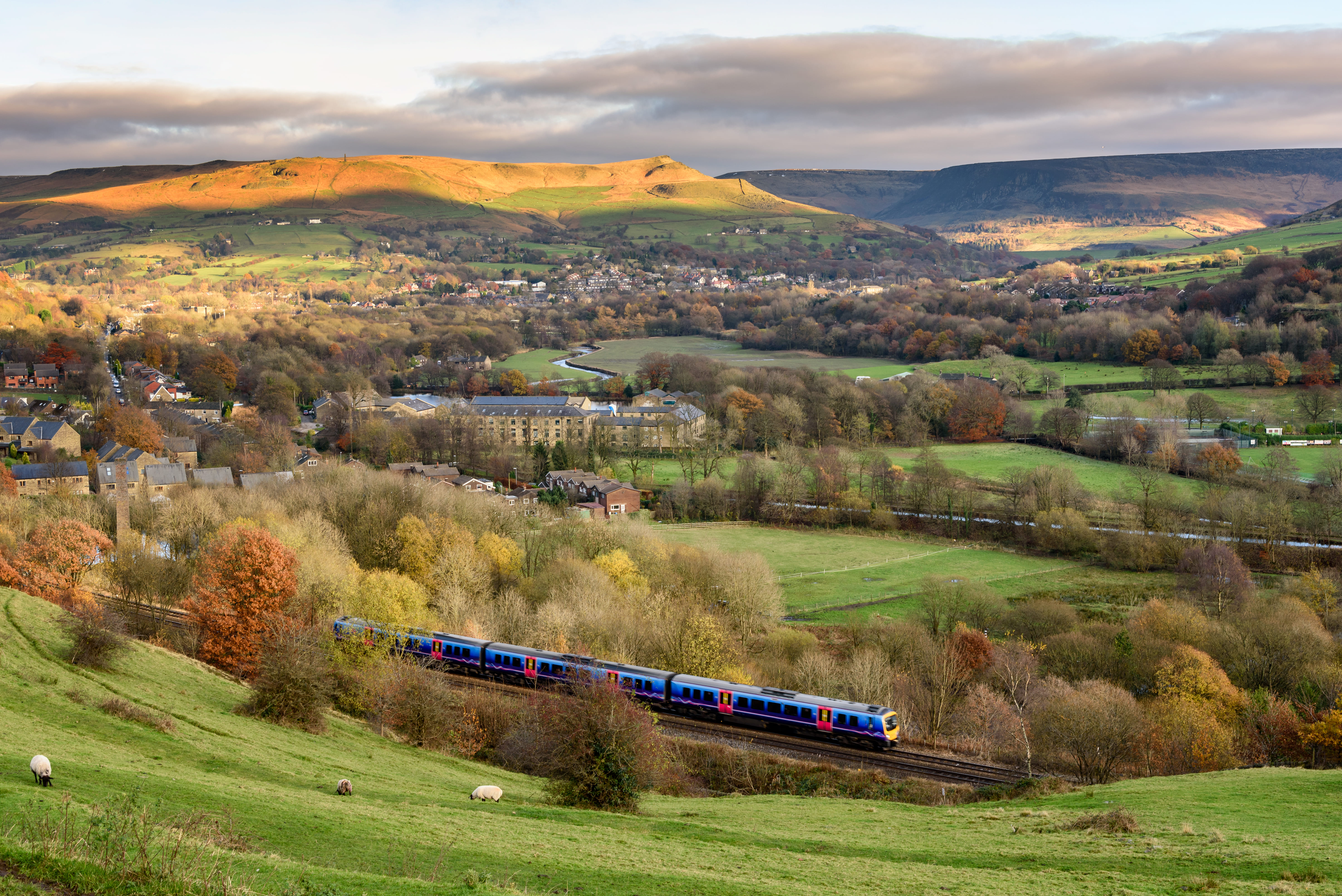 Passenger train passing through british countryside near greater Manchester, England.