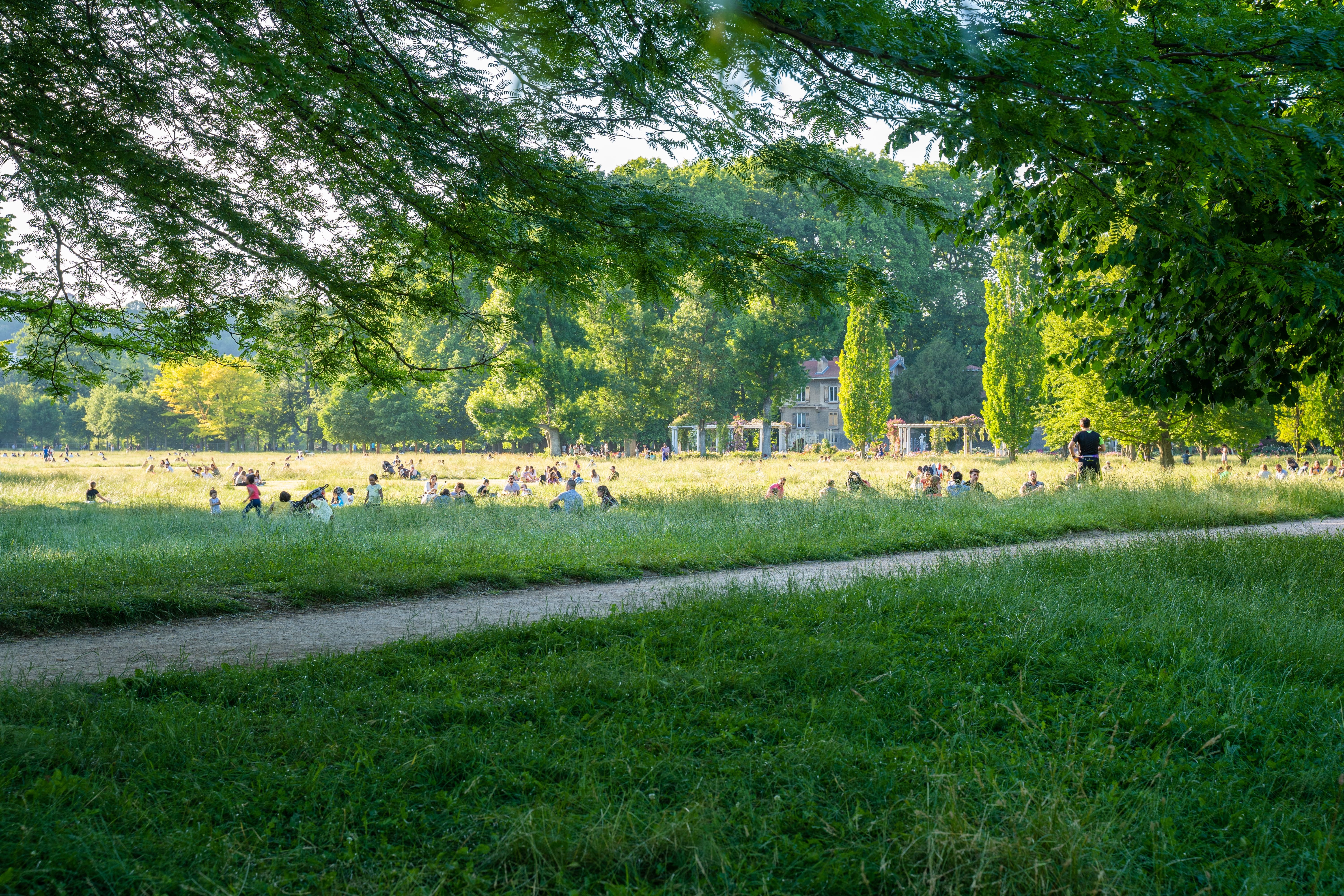 People lounging on the grass on a sunny day in Parc de la Tête d’Or in Lyon, France