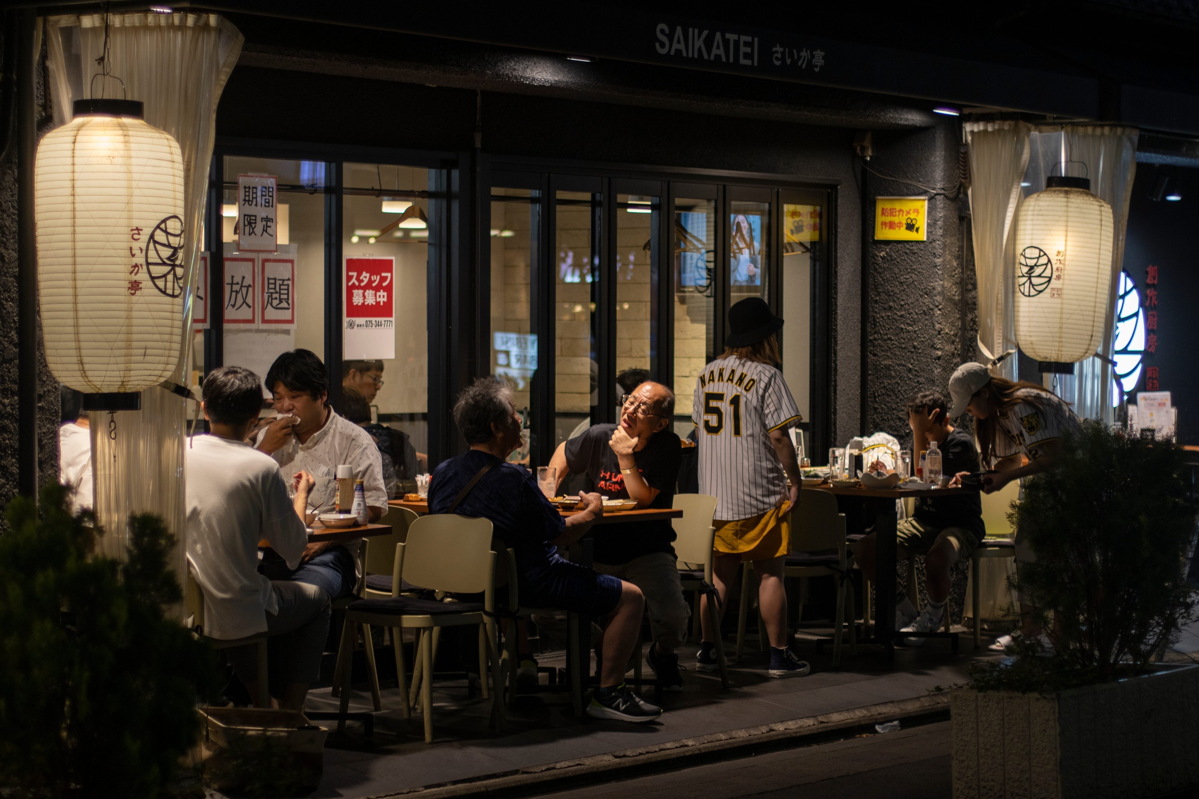 People eating outside busy restaurant at night in Kyoto, Japan